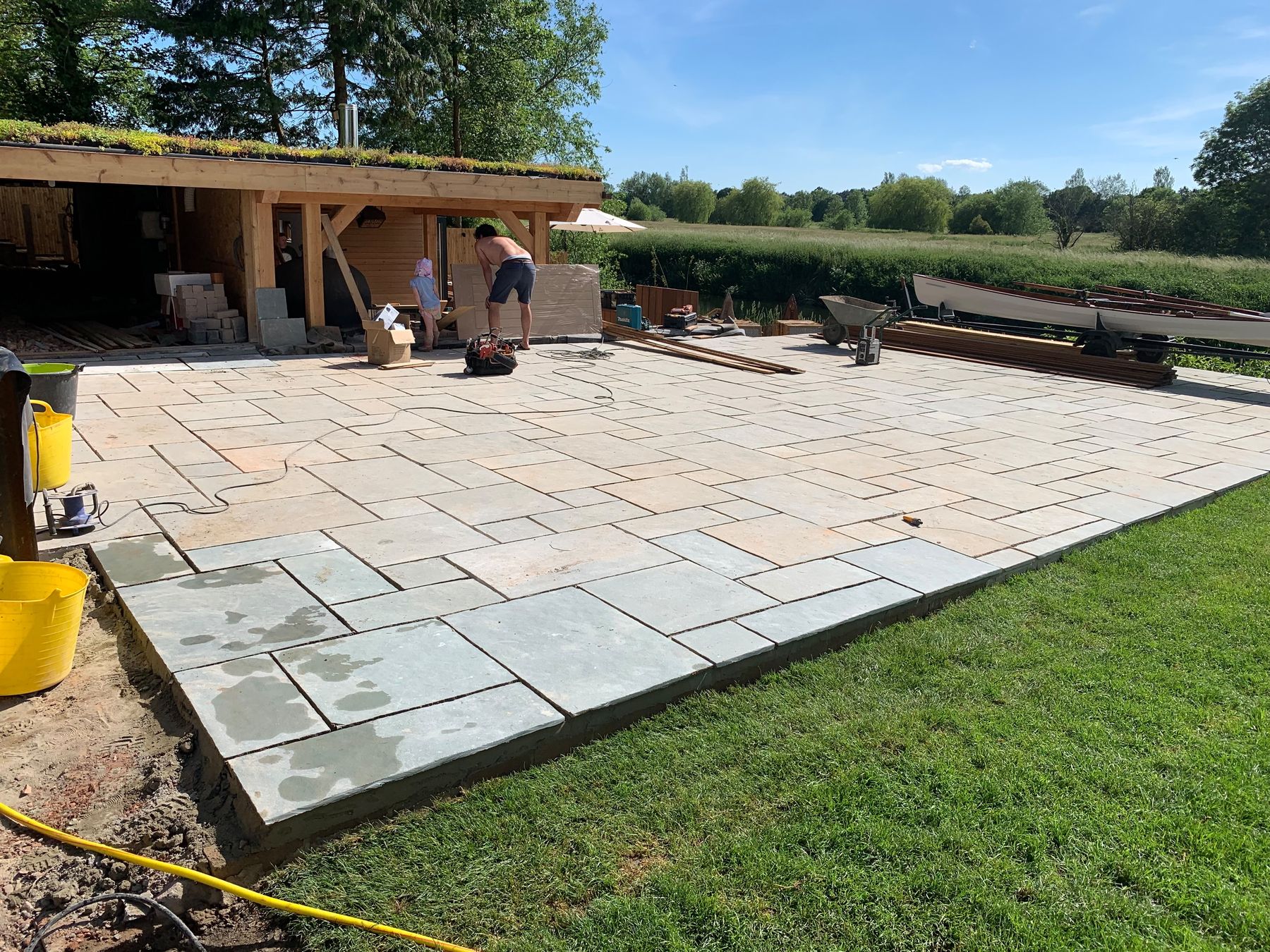 Large sandstone patio being laid beside a river